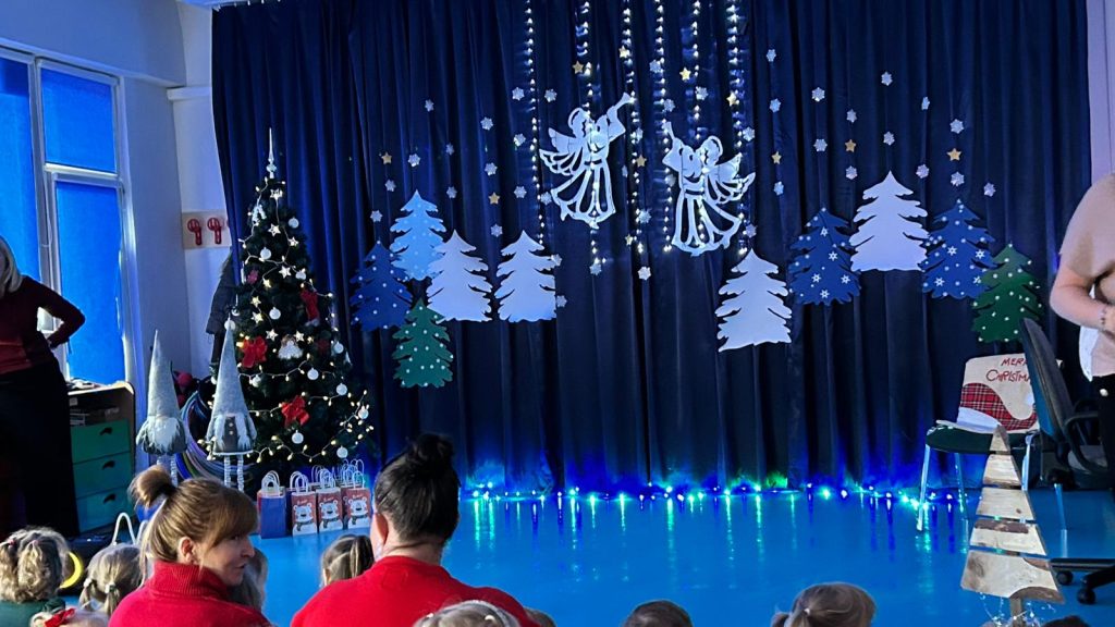 ubrana choinka, dekoracja przedstawiająca dwa anioły, w tle choinki i światełka